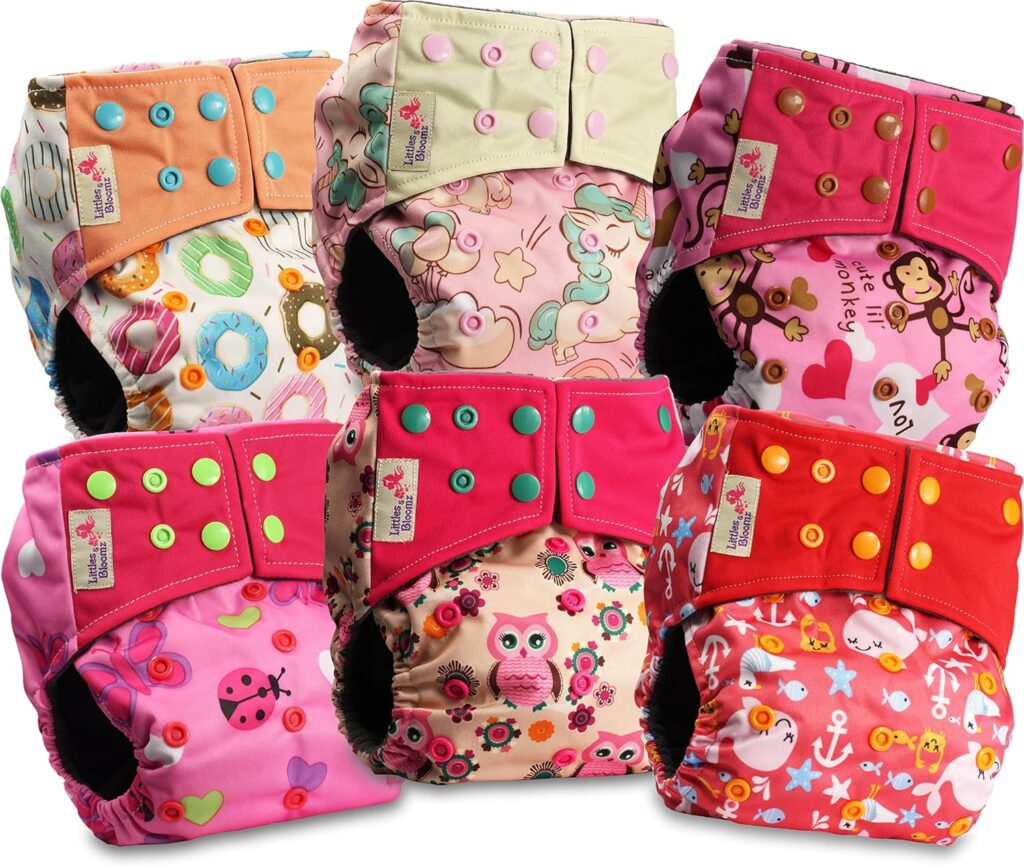 Stack of colourful washable cloth nappies with cute prints and adjustable buttons.